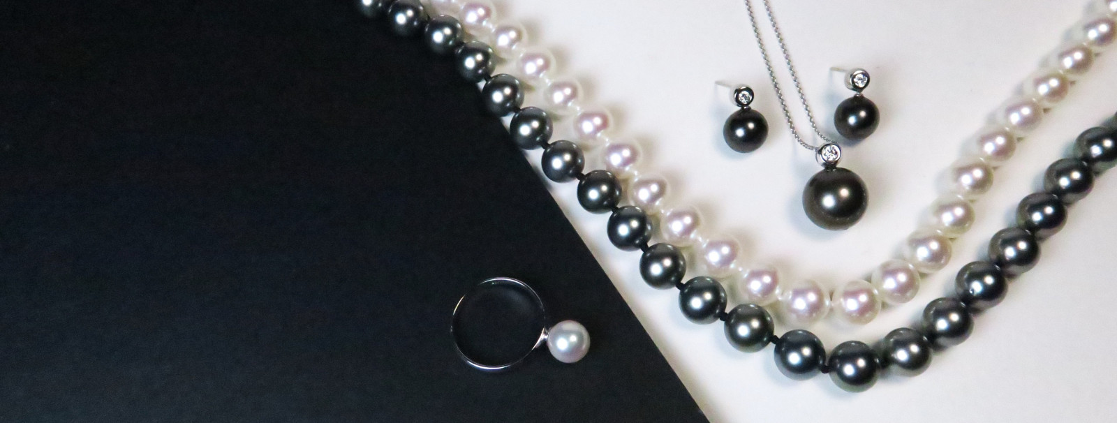 Exklusiver echter Perlenschmuck der gesamten Kollektion mit handverlesenen Perlenketten, Ringen und Ohrringen vor edlem, dunklem Hintergrund.